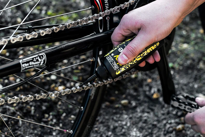closeup of a chain being lubricated for regular bike maintenance