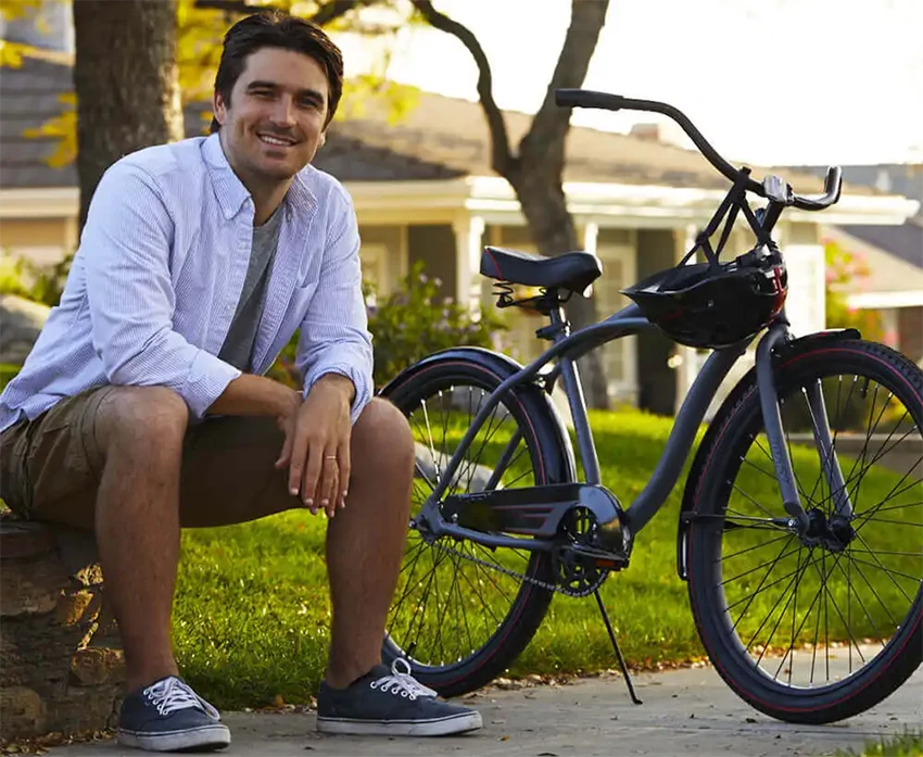 man sitting next to a huffy electric bike