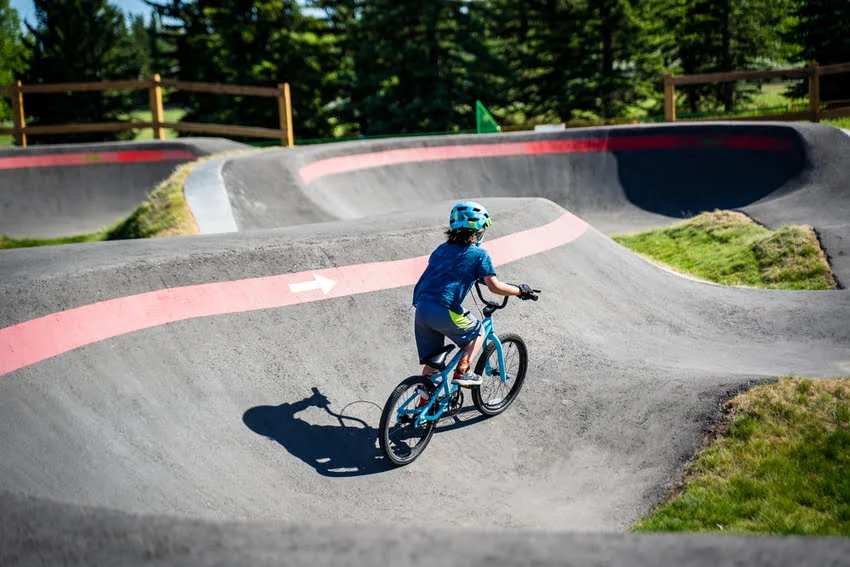 young boy in blue clothes riding a bike on a pump track