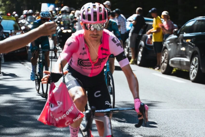 cyclist in pink jersey grabbing a pink musette bag