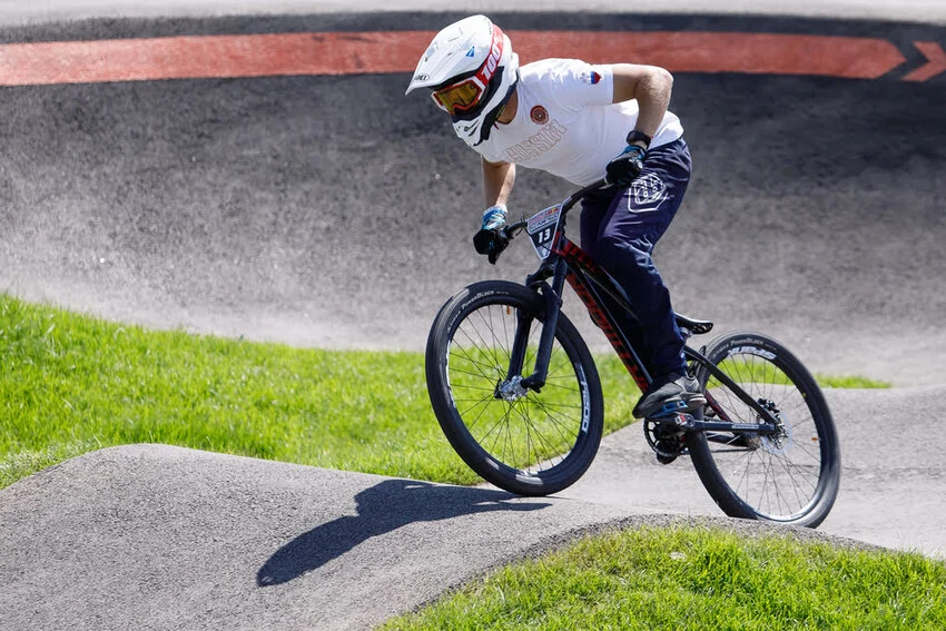 a cyclist riding a bmx bike on a pump track wearing a full-face helmet