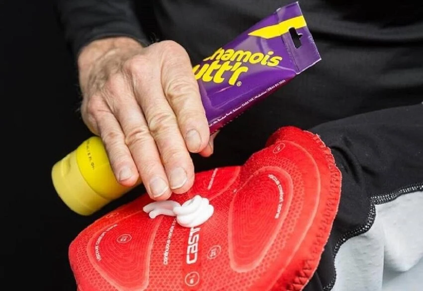 person applying chamois cream to cycling bibs