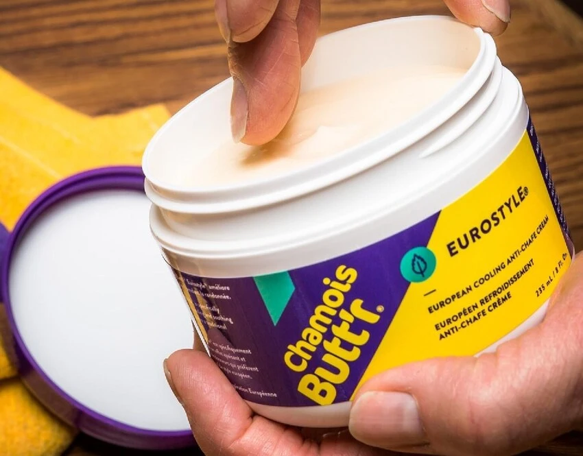 person scooping chamois cream out of a pot using their fingers